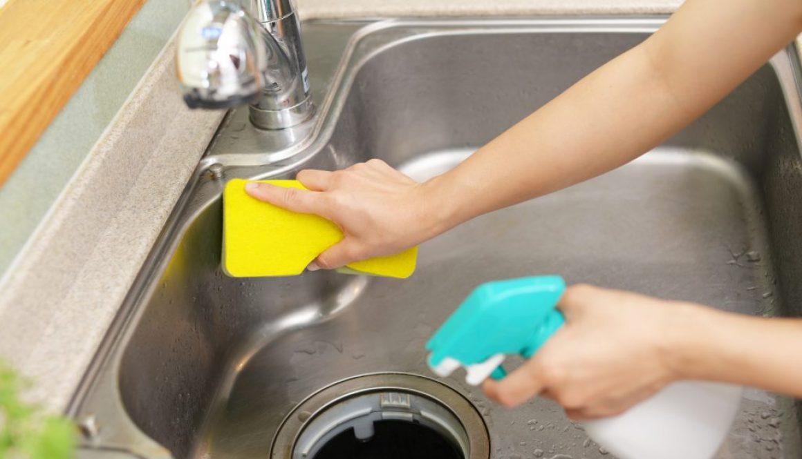 cleaning kitchen sink with sponge and cleaning detergent